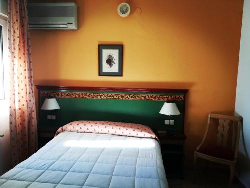 a bedroom with a bed and an orange wall at Hotel Restaurante Logasasanti in Andújar
