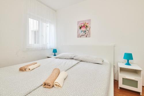 a white bedroom with a bed with towels on it at Apartments Nina in Umag