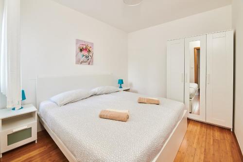 a white bedroom with a bed with two pillows on it at Apartments Nina in Umag