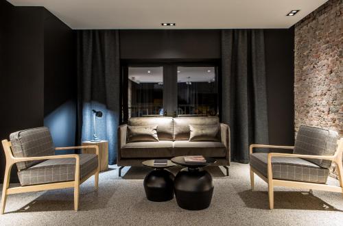 a living room with a couch and two chairs at Hôtel Louvre-Lens - Esprit de France in Lens