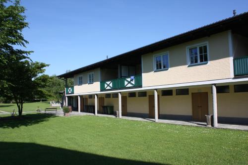 a building with a green balcony and a grass yard at Ferienwohnungen am See in Obertrum am See