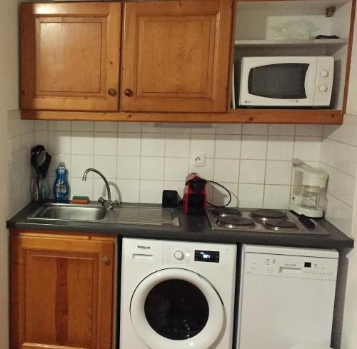 een keuken met een wasmachine en een magnetron bij Byne - Residence Le Cheval Blanc Valfréjus in Valfréjus