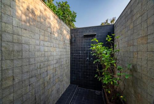 a brick wall with a door and a plant at SaffronStays Masaya, Alibaug - pet-friendly villa with alfresco dining in Alibaug