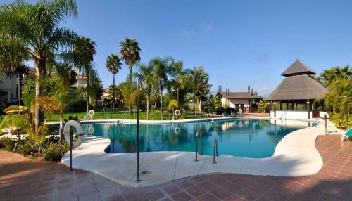 エステポナにあるEl Campanario del Paraísoのヤシの木とガゼボのあるリゾートのプールを利用できます。
