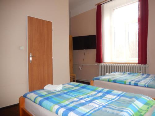 two beds in a small room with a window at PENZION MANĚTÍN u Sv. Barbory in Manětín