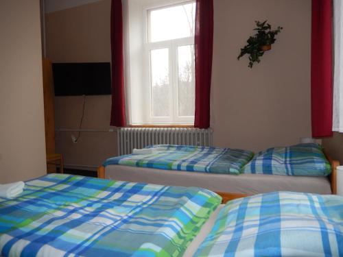 two beds in a room with a window at PENZION MANĚTÍN u Sv. Barbory in Manětín
