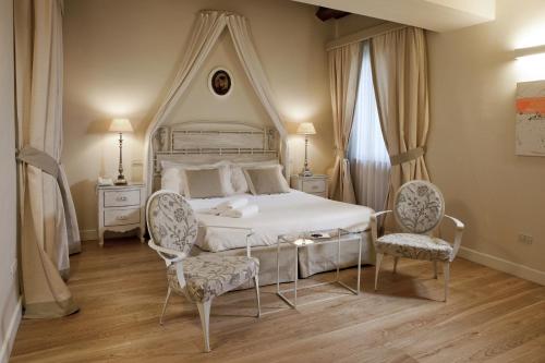 um quarto com uma cama branca e 2 cadeiras em Hotel & Residenza 100 Torri em Ascoli Piceno