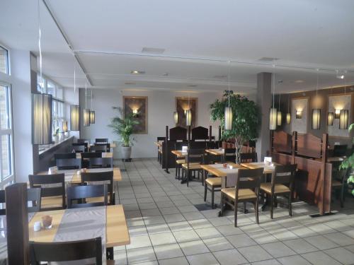 a dining room with tables and chairs in a restaurant at Hotel Pension Am Hafen in Norddeich