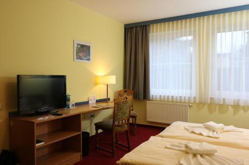 a hotel room with two beds and a desk with a television at Radduscher Hafen in Vetschau