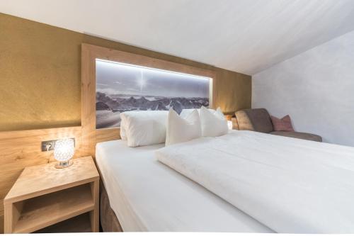 a bedroom with a large white bed with a window at Das Hochegg - Apartments in Obergurgl