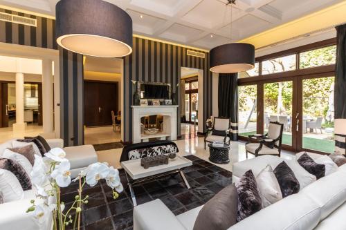 a living room with white furniture and a fireplace at Houst Holiday Homes - Al Barari in Dubai