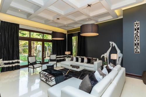 a living room with a white couch and chairs at Houst Holiday Homes - Al Barari in Dubai