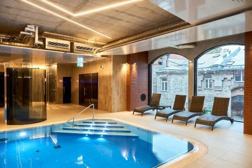 a large swimming pool in a building with chairs at Metropol Spa Hotel in Tallinn