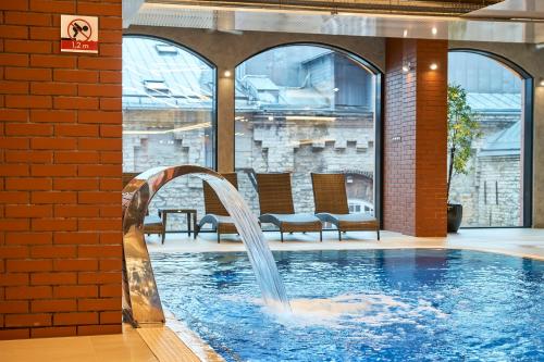 a swimming pool with a fountain and chairs in it at Metropol Spa Hotel in Tallinn