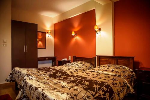 a bedroom with a bed and orange walls at Andromeda Hotel Limni Plastira in Koutsodímos