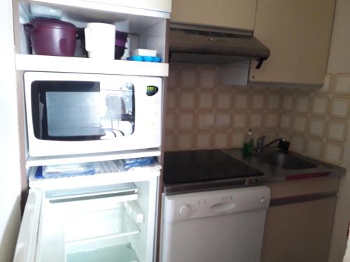 une petite cuisine avec un micro-ondes et une cuisinière dans l'établissement C213 Appartement Vue Mer Terrasse, Parking, à Arcachon