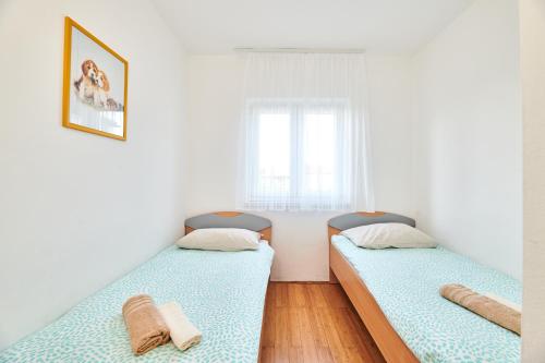 two beds in a small room with a window at Apartments Nina in Umag