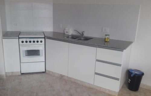 a white kitchen with a sink and a stove at Bahiaxdia Saavedra in Bahía Blanca