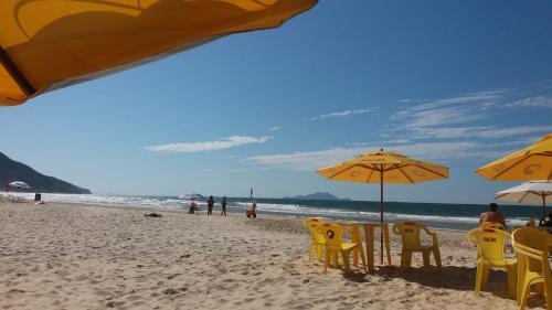 una playa con sillas y sombrillas amarillas y el océano en LINDO APARTAMENTO NOS INGLESES, en Florianópolis