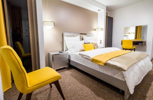 a bedroom with a bed and two yellow chairs at Dumbrava Residence in Sibiu