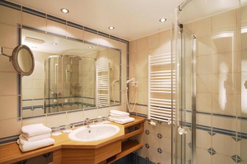 a bathroom with a sink and a shower and a mirror at INSELHUS Apartments in Baltrum