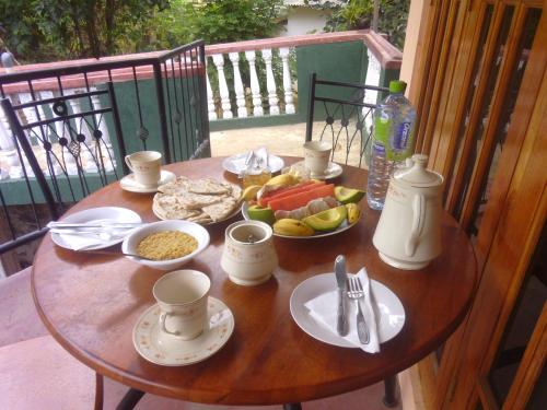 uma mesa de madeira com comida e bebidas numa varanda em Jasmine Garden Inn em Ella