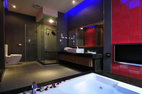 a bathroom with a tub and a shower and a television at One + One Motel in Longtan