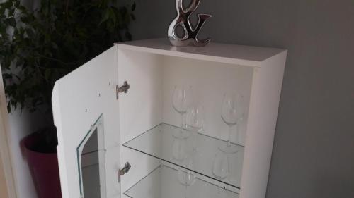 a white cabinet with glass shelves and a pair of scissors at ARS VIP Apartment in Novi Sad