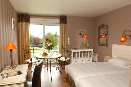 a hotel room with a bed and a table and chairs at Logis L'Ermitage Hôtel & Restaurant in Saulges