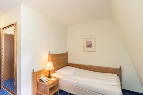 a bedroom with a bed and a mirror and a phone at Hotel Schloss Neustadt-Glewe in Neustadt-Glewe