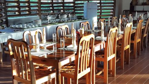 a long wooden table and chairs in a room at Kibale Guest Cottages in Fort Portal