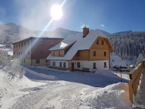 a house in the snow with the sun behind it at Tauernhaus Appartment in Planneralm