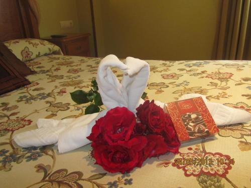 a bed with towels and red roses and a book at Hotel Marfrei in Hinojedo