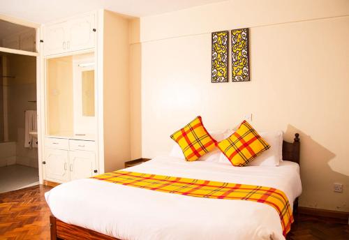 a bedroom with a bed with two pillows on it at Njema Court Apartment in Nairobi