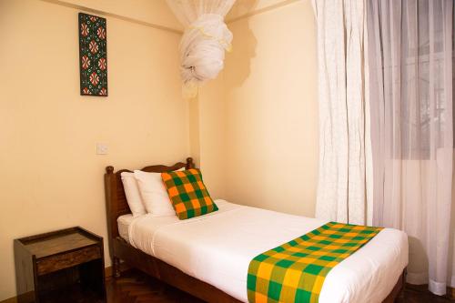 a small bedroom with a bed and a window at Njema Court Apartment in Nairobi