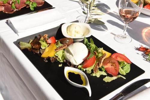 a black plate with a salad on a table at Résidence Les Calanques in Ajaccio