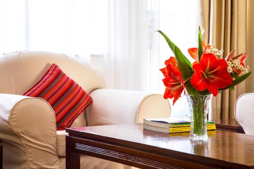 a vase of red flowers sitting on a table at Njema Court Apartment in Nairobi
