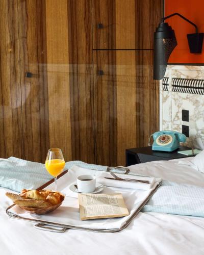 a breakfast tray with a glass of orange juice and a book at Hotel Les Bains Paris in Paris