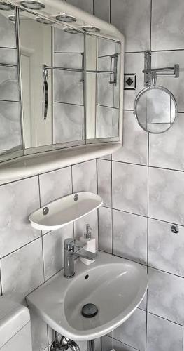 a white bathroom with a sink and a mirror at Ferienhaus "Auberge Jolie" in Aachen