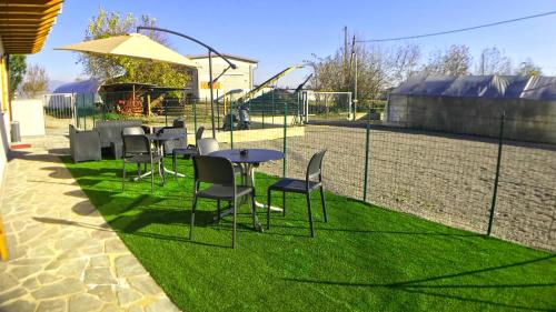 a group of chairs and tables and an umbrella on grass at Bonne Nuit Guest House in Azzano San Paolo