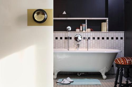 a bathroom with a white tub and a black wall at Hotel Les Bains Paris in Paris