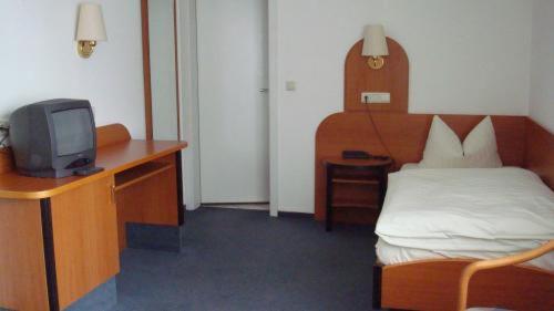 a bedroom with a bed and a desk with a tv at Hotel zur Eisenbahn in Rodgau