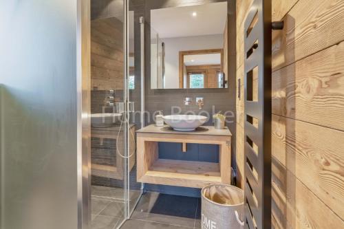 a bathroom with a sink and a glass shower at Chalet Annelya in Combloux