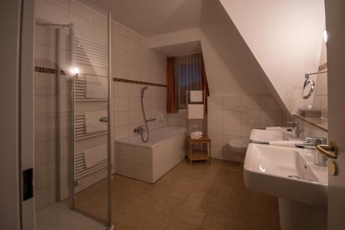 a bathroom with a shower and a tub and a sink at Hotel Stadt Aurich in Aurich