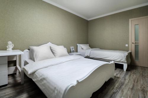 a bedroom with two beds with white sheets and a desk at PaulMarie Apartments on Yakubovskogo str. in Mogilev