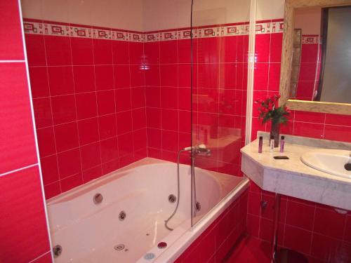 a red tiled bathroom with a tub and a sink at Hotel Marfrei in Hinojedo