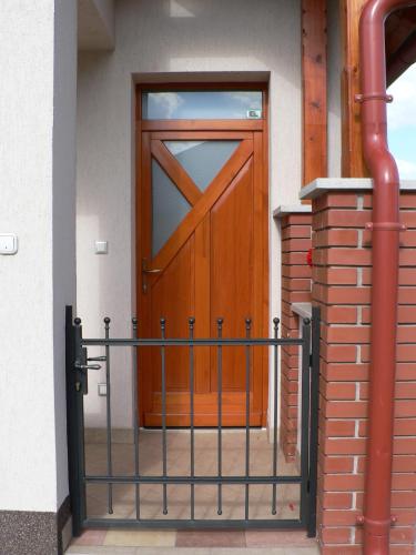 a wooden door with a metal fence in front of it at Oázis Apartmanok in Mórahalom