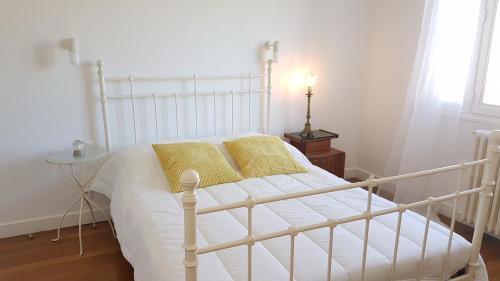 Una cama blanca con almohadas amarillas en un dormitorio en maison spacieuse renovée en Longeville-en-Barrois
