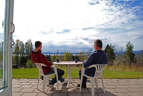 two men sitting at a table on a patio at STF Orsa Hostel in Orsa