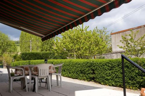 a table and chairs under a patio umbrella at Les Louchardes in La Rochepot